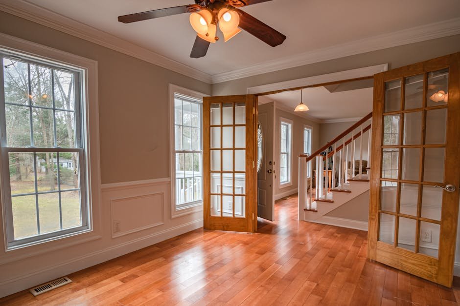 pexels-photo-3935316-3935316 Spacious living room with wooden French doors and ceiling fan, showcasing contemporary interior design.